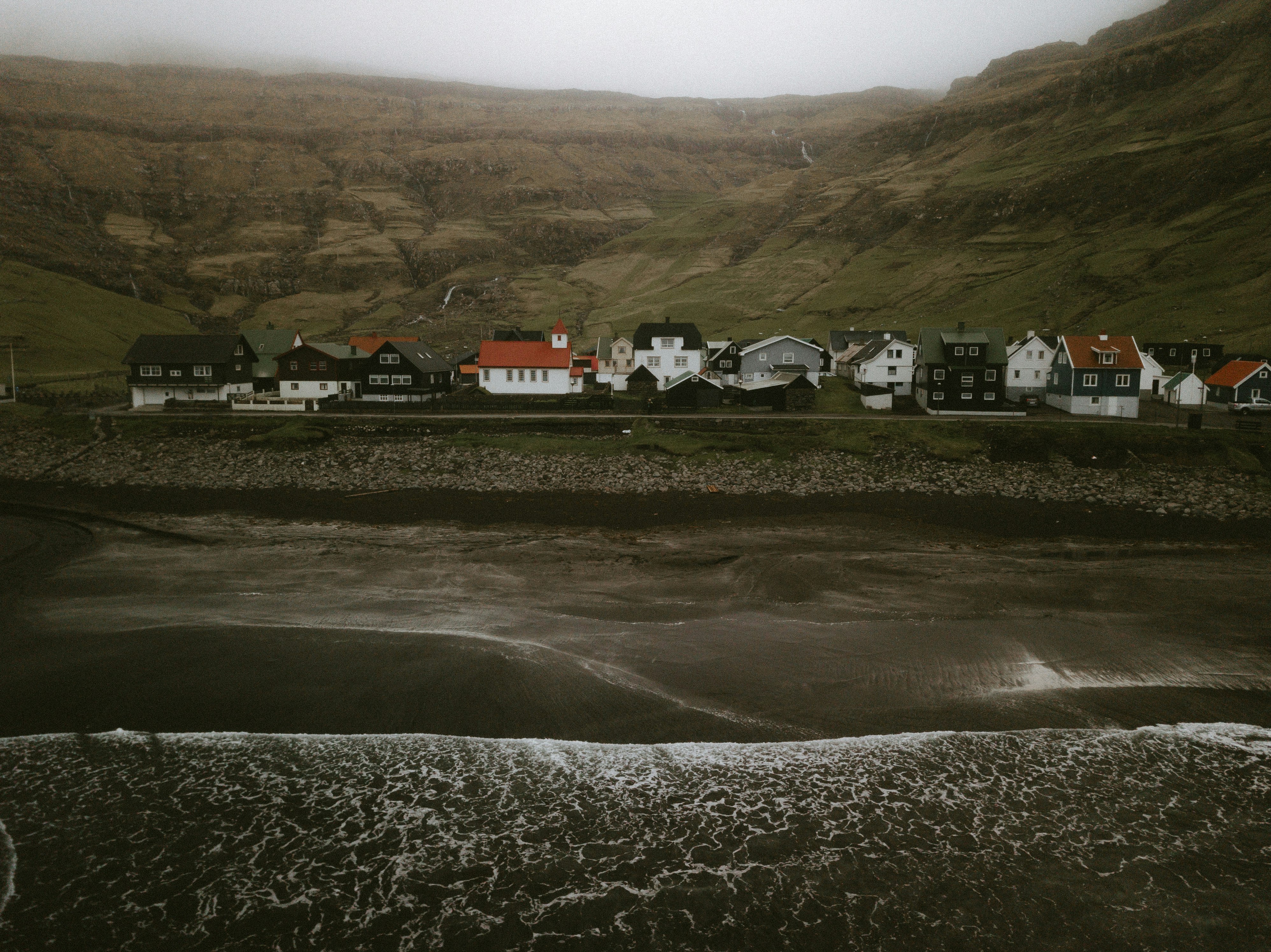 photography of houses beside green mountain during daytime